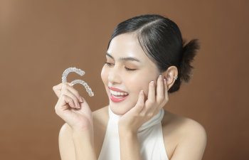 happy woman holds invisalign in hand